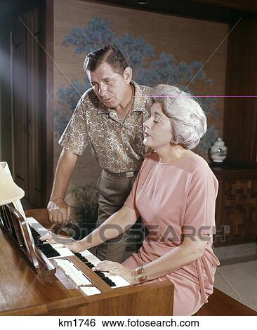 1950S 1960S Mature Couple Man And Woman Playing And Singing Together At Home Organ Keyboard Instrument View Large Photo Image Stock Photograph - 1950S 1960S Mature Couple Man And Woman Playing And Singing Together At Home Organ Keyboard Instrument. Fotosearch