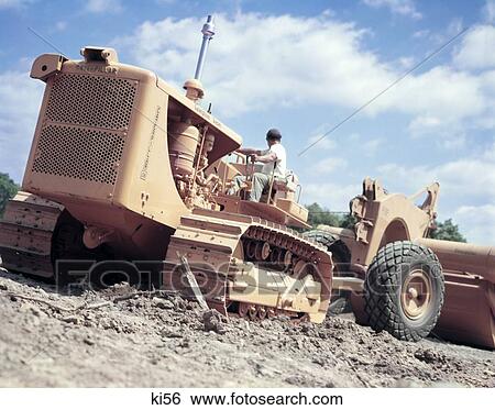 1950S 1960S Retro Man Heavy Equipment Operator Driving Catepiller Bulldozer Tractor Pulling Earth Mover Road Grader View Large Photo Image Stock Photograph - 1950S 1960S Retro Man Heavy Equipment Operator Driving Catepiller Bulldozer Tractor Pulling Earth Mover Road Grader. Fotosearch