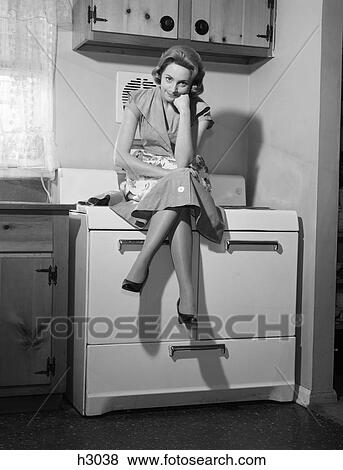 1950S 1960S Woman Housewife Sitting Atop On Stove Angry Frustrated Serious Facial Expression View Large Photo Image Stock Photo - 1950S 1960S Woman Housewife Sitting Atop On Stove Angry Frustrated Serious Facial Expression . Fotosearch