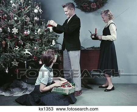 1950s ２人の少女たち そして １人の少年 クリスマスツリーを飾ること で 装飾 十代の若者たち ティーネージャー 休日 ストックイメージ Kx1353 Fotosearch