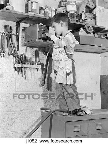 1950S 4 Year Old Boy In Garage Tool Shed Standing On Cabinet To Reach Box On Shelf View Large Photo Image Stock Image - 1950S 4 Year Old Boy In Garage Tool Shed Standing On Cabinet To Reach Box On Shelf . Fotosearch