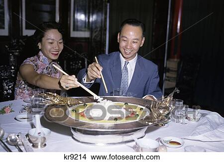 1950S Asian Couple Man Woman Smiling Eating In Hong Kong Restaurant Large Entree Chinese Food Chopsticks View Large Photo Image Picture - 1950S Asian Couple Man Woman Smiling Eating In Hong Kong Restaurant Large Entree Chinese Food Chopsticks. Fotosearch