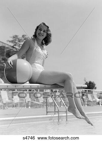 1950S Bathing Beauty In Satin One-Piece Sitting On Diving Board With Legs Hanging Off Holding Beach Ball At Side View Large Photo Image Stock Photograph - 1950S Bathing Beauty In Satin One-Piece Sitting On Diving Board With Legs Hanging Off Holding Beach Ball At Side . Fotosearch