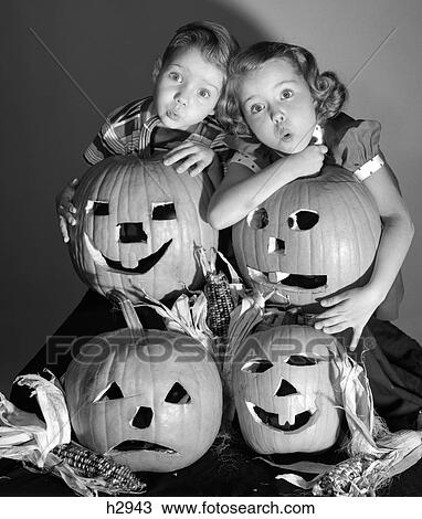 1950S Boy And Girl Standing Behind And Or Holding Four Jack-O-Lanterns With Indian Corn Making Spooky Faces View Large Photo Image Stock Image - 1950S Boy And Girl Standing Behind And Or Holding Four Jack-O-Lanterns With Indian Corn Making Spooky Faces . Fotosearch