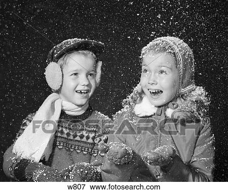 1950S Boy Girl In Winter Dress Hats Gloves Ear Muffs Scarf Smiling Happy Fake Snow Falling Studio Shot View Large Photo Image Stock Photo - 1950S Boy Girl In Winter Dress Hats Gloves Ear Muffs Scarf Smiling Happy Fake Snow Falling Studio Shot . Fotosearch