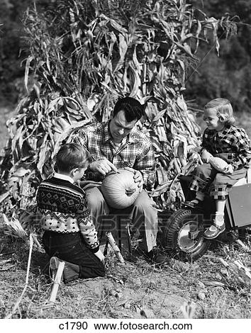 1950S Boy & Girl Sitting In Front Of Corn Stalks Watching Father Carve Pumpkin View Large Photo Image Stock Image - 1950S Boy & Girl Sitting In Front Of Corn Stalks Watching Father Carve Pumpkin . Fotosearch