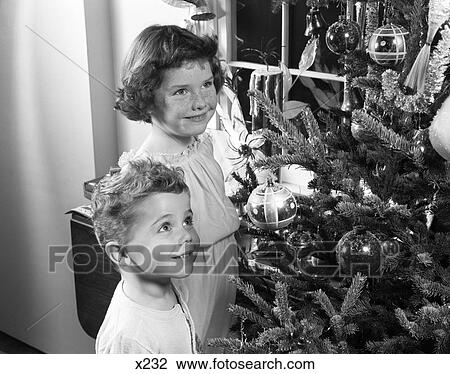 1950S Boy Girl Smiling Up At Christmas Tree Decorations Ornaments Pine Fir Candle In Window Wishing Dreaming View Large Photo Image Stock Image - 1950S Boy Girl Smiling Up At Christmas Tree Decorations Ornaments Pine Fir Candle In Window Wishing Dreaming . Fotosearch