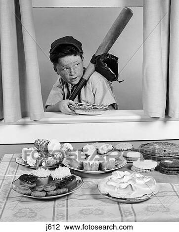 Stock Image - 1950S Boy In Baseball Garb With Bat Sneaking Pie Through Open Window . Fotosearch