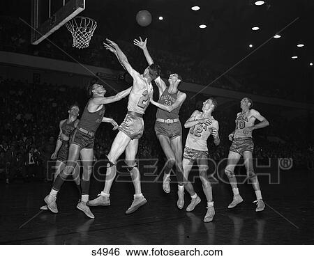 Stock Photograph - 1950S College Basketball Baltimore Warriors Philadelphia Ball Is In Air Players Jumping Under Hoop . Fotosearch