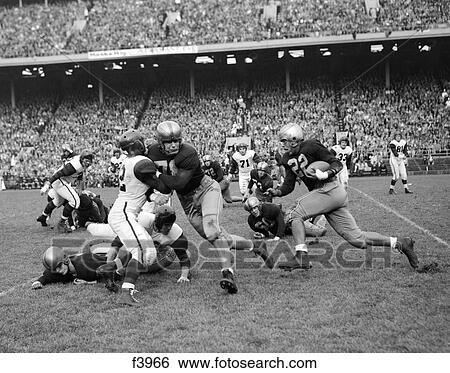 1950S College Football Game Showing Blockers Making Tackles For Running Back With Capacity Crowd In Stands In Background View Large Photo Image Stock Photograph - 1950S College Football Game Showing Blockers Making Tackles For Running Back With Capacity Crowd In Stands In Background. Fotosearch