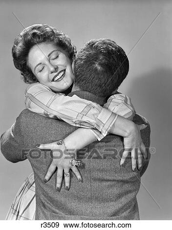 1950S Couple Happy Smiling Woman Facing Forward Hands Draped Over Mans Back Hugging Embracing Thrilled Love View Large Photo Image Stock Photo - 1950S Couple Happy Smiling Woman Facing Forward Hands Draped Over Mans Back Hugging Embracing Thrilled Love . Fotosearch