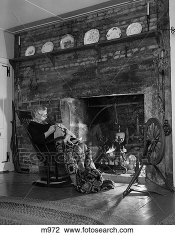 1950S Elderly Woman In Rocker In Front Of Fireplace Doing Needlework