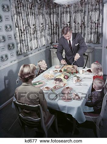 1950S Family 5 Sit At Dining Room Table Dad Carves Turkey At Head Of Table Mom Kids Curtains Interior Holiday Meal View Large Photo Image Stock Photo - 1950S Family 5 Sit At Dining Room Table Dad Carves Turkey At Head Of Table Mom Kids Curtains Interior Holiday Meal. Fotosearch