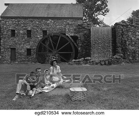 1950S Family Picnicking In Grass In Front Of Old Stone Water Mill View Large Photo Image Picture - 1950S Family Picnicking In Grass In Front Of Old Stone Water Mill. Fotosearch
