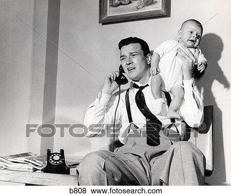 Stock Photo - 1950S Father Holding Baby While On The Phone . Fotosearch