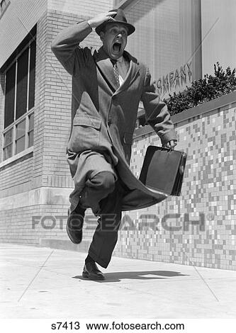 1950S Frantic Man Running Down Street Holding Hat On With Hand Carrying Briefcase Wearing Top Coat Commuter Businessman View Large Photo Image Stock Image - 1950S Frantic Man Running Down Street Holding Hat On With Hand Carrying Briefcase Wearing Top Coat Commuter Businessman. Fotosearch