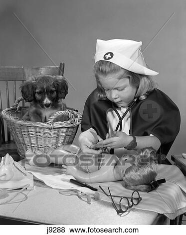 1950S Girl Dressed In A Nurse'S Uniform Putting Bandages On A Doll While A Puppy Dog In A Basket Behind Her Watches View Large Photo Image Stock Photo - 1950S Girl Dressed In A Nurse'S Uniform Putting Bandages On A Doll While A Puppy Dog In A Basket Behind Her Watches. Fotosearch