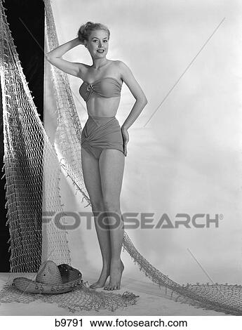 1950S Glamour Girl Pose In Studio Draped With Fishing Net Woman In Two Piece Swim Bathing Suit Fashion Strapless Bra Top View Large Photo Image Stock Image - 1950S Glamour Girl Pose In Studio Draped With Fishing Net Woman In Two Piece Swim Bathing Suit Fashion Strapless Bra Top . Fotosearch