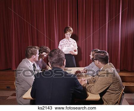 Stock Image - 1950S Group 6 Teens Boys Girls Meeting Table Conference Girl Reading From Paper Chairperson Student Government Council. Fotosearch