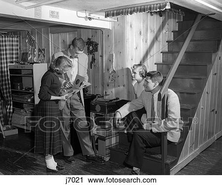 Stock Image - 1950S Group Teens Boys Girls Playing Records On Phonograph Knotty Pine Rec Room . Fotosearch