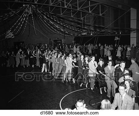 Stock Image - 1950S High School Dance With Large Crowd Of Teen Couples In A Conga Line Snaking Through The Gymnasium . Fotosearch