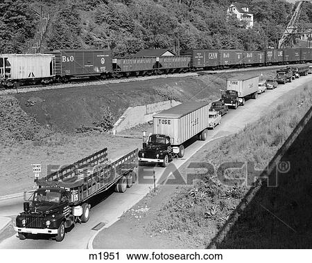 1950S Line Of Traffic With Many Trucks & Cars & Freight Train Passing On Adjacent Hillside View Large Photo Image Stock Image - 1950S Line Of Traffic With Many Trucks & Cars & Freight Train Passing On Adjacent Hillside . Fotosearch