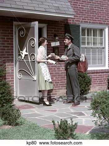 Stock Image - 1950S Mailman Delivering Mail To Woman Brick Suburban Home Aluminum Screen Door Delivery Man Housewife Mailbag Letter. Fotosearch