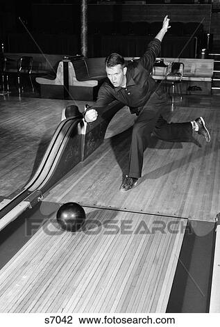 Stock Image - 1950S Man Dressed Entirely In Black Letting Go Of Bowling Ball Holding Proper Form . Fotosearch