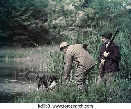 1950S Man Woman Couple Shotgun Gunning Hunting By Lake Pond Black Dog Labrador Retriever Returning Water Fowl Duck View Large Photo Image Stock Photo - 1950S Man Woman Couple Shotgun Gunning Hunting By Lake Pond Black Dog Labrador Retriever Returning Water Fowl Duck. Fotosearch