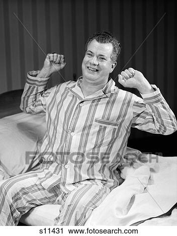 1950S Middle Aged Man Sitting Edge Of Bed Striped Pajamas Smiling Stretching Arms Bent Shoulder View Large Photo Image Stock Image - 1950S Middle Aged Man Sitting Edge Of Bed Striped Pajamas Smiling Stretching Arms Bent Shoulder . Fotosearch