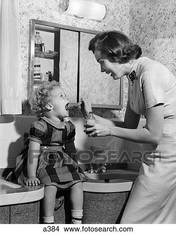1950S Mother Feeding Medicine To Young Daughter With Mouth Wide Open Sitting On Bathroom Sink View Large Photo Image Picture - 1950S Mother Feeding Medicine To Young Daughter With Mouth Wide Open Sitting On Bathroom Sink . Fotosearch