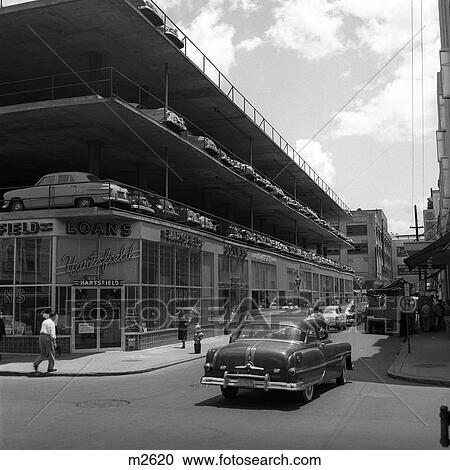 Stock Image - 1950S New Type Parking Lot Three Story Bulding Architecture Car On Street Pedestrian New Orleans La Retro. Fotosearch