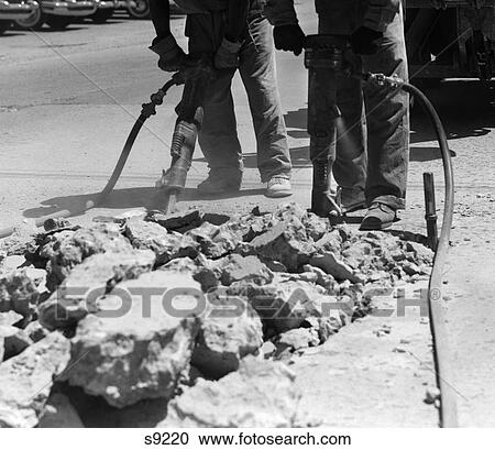 Stock Image - 1950S Pair Of Workers Shown Waist-Down Using Jackhammers On Street . Fotosearch