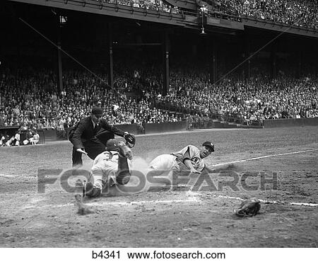 Stock Image - 1950S Professional Major League Baseball Game Runner Sliding Into Home Base As Umpire Signals Safe . Fotosearch