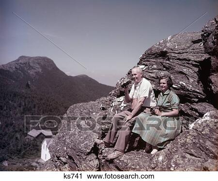 1950S Senior Couple On Rocks Top Of Mount Mansfield Vt Man Has Binoculars Woman In Green Dress Camera On Neck Retire Travel View Large Photo Image Stock Image - 1950S Senior Couple On Rocks Top Of Mount Mansfield Vt Man Has Binoculars Woman In Green Dress Camera On Neck Retire Travel . Fotosearch