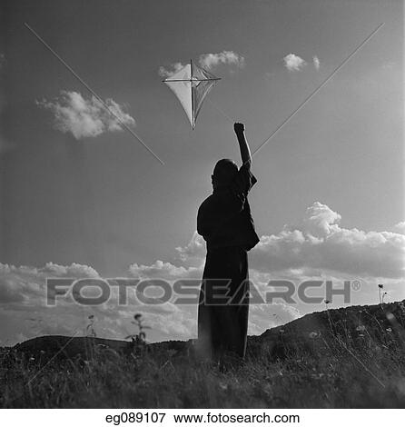 1950S Silhouette Of Boy Flying Kite Against Sky With Clouds View Large Photo Image Stock Photo - 1950S Silhouette Of Boy Flying Kite Against Sky With Clouds. Fotosearch