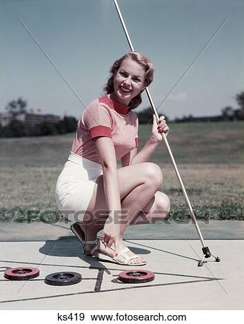 1950S Smiling Blonde Woman Kneeling On Shuffleboard Holding Cue Point At Disk Wear White Shorts Shuffle Game View Large Photo Image Stock Photo - 1950S Smiling Blonde Woman Kneeling On Shuffleboard Holding Cue Point At Disk Wear White Shorts Shuffle Game. Fotosearch