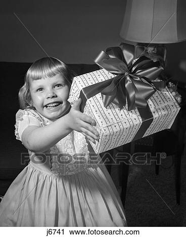 1950S Smiling Girl Holding Up Gift Wrapped Present View Large Photo Image Stock Image - 1950S Smiling Girl Holding Up Gift Wrapped Present . Fotosearch