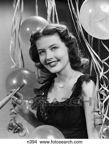 1950S Smiling Woman Black Dress Pearls Holding Noise Maker Streamers Balloons Background New Year Party View Large Photo Image Picture - 1950S Smiling Woman Black Dress Pearls Holding Noise Maker Streamers Balloons Background New Year Party . Fotosearch