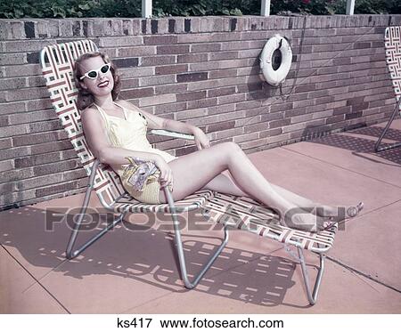 1950S Smiling Woman Sun Bathing Wearing Sunglasses In Deck Chair Chaise Longue Life Perserver Buoy On Stone Wall View Large Photo Image Stock Photo - 1950S Smiling Woman Sun Bathing Wearing Sunglasses In Deck Chair Chaise Longue Life Perserver Buoy On Stone Wall. Fotosearch