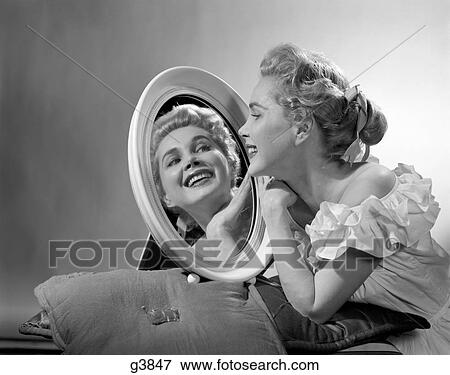 1950S Smiling Woman Wearing An Off The Shoulder Ruffled Blouse Looking Into A Oval Mirror At Her Reflection View Large Photo Image Stock Photo - 1950S Smiling Woman Wearing An Off The Shoulder Ruffled Blouse Looking Into A Oval Mirror At Her Reflection . Fotosearch