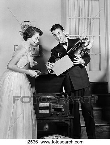 1950S Teen Couple Boy And Girl In Prom Formal Wear Playing Phonograph Records In Home Living Room View Large Photo Image Stock Photograph - 1950S Teen Couple Boy And Girl In Prom Formal Wear Playing Phonograph Records In Home Living Room . Fotosearch