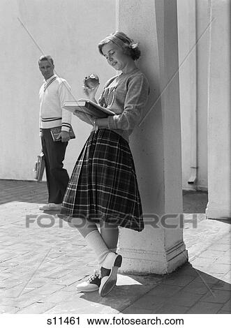 1950S Teen School Girl Plaid Skirt Lean Against Column Eating Apple Read Book As Boy Walks By In Background View Large Photo Image Stock Image - 1950S Teen School Girl Plaid Skirt Lean Against Column Eating Apple Read Book As Boy Walks By In Background . Fotosearch