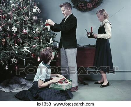 1950S Two Girls And One Boy Decorating Christmas Tree With Ornaments Teens Teenagers Holiday View Large Photo Image Stock Image - 1950S Two Girls And One Boy Decorating Christmas Tree With Ornaments Teens Teenagers Holiday . Fotosearch