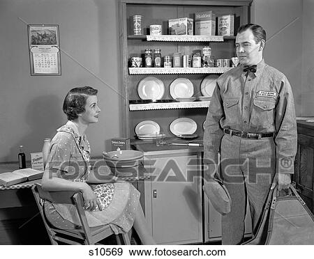 1950S Woman Apron Sitting At Kitchen Table Talking To Repairman Or Husband In Uniform Housewife Food Boxes On Shelves View Large Photo Image Stock Photo - 1950S Woman Apron Sitting At Kitchen Table Talking To Repairman Or Husband In Uniform Housewife Food Boxes On Shelves. Fotosearch