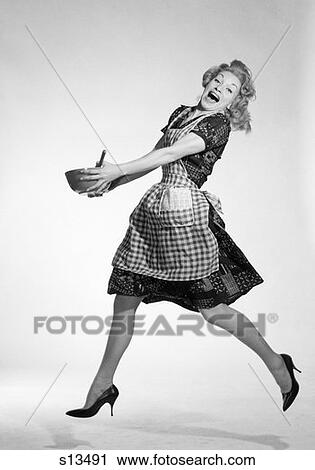 1950S Woman In Checkered Apron Jumping With Glee Holding Spoon Mixing Bowl With Both Hands Big Smile View Large Photo Image Stock Image - 1950S Woman In Checkered Apron Jumping With Glee Holding Spoon Mixing Bowl With Both Hands Big Smile. Fotosearch