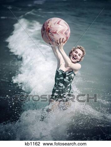 1950S Woman Jumping In Surf Holding Up Beach Ball View Large Photo Image Stock Image - 1950S Woman Jumping In Surf Holding Up Beach Ball . Fotosearch