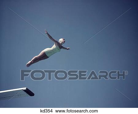 Picture - 1950S Woman Jumping Off Diving Board Against Blue Sky Graphic Bathing Cap One Piece Suit Athletic Sport Flying Midair . Fotosearch