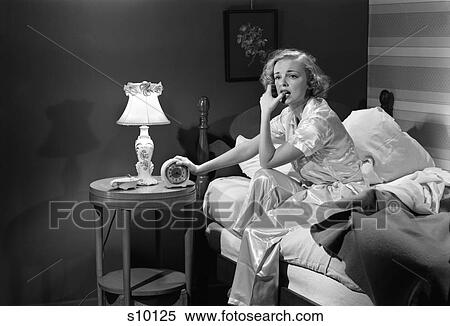 1950S Woman Silk Pajamas Sitting Edge Of Bed Stressed Serious Worried Sleepless Holding Alarm Clock Night Table Lamp Insomnia View Large Photo Image Stock Photography - 1950S Woman Silk Pajamas Sitting Edge Of Bed Stressed Serious Worried Sleepless Holding Alarm Clock Night Table Lamp Insomnia. Fotosearch