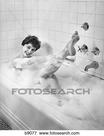 1950S Woman Taking A Bubble Bath In Tub Smiling Holding Leg With Her Hand Tiled Walls Soap Suds Relax Glamour Sexy View Large Photo Image Stock Photo - 1950S Woman Taking A Bubble Bath In Tub Smiling Holding Leg With Her Hand Tiled Walls Soap Suds Relax Glamour Sexy. Fotosearch